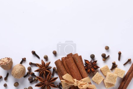 Different spices and nuts on white table, flat lay. Space for text