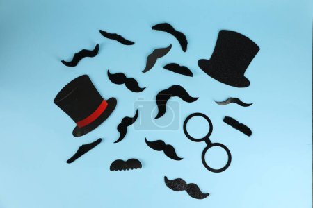 Téléchargez les photos : Fausses moustaches, chapeaux et verres sur fond bleu clair, pose plate - en image libre de droit