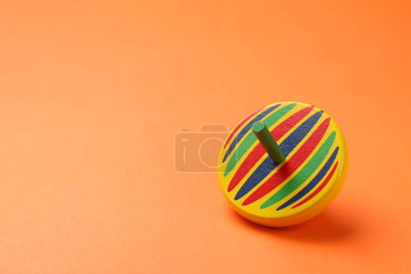 One colorful spinning top on orange background, space for text