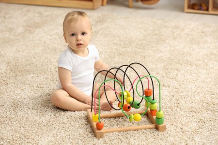 Children toys. Cute little boy and bead maze on rug at home
