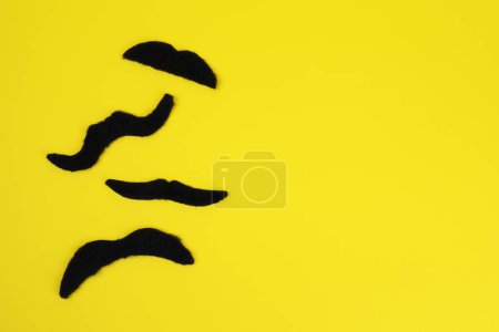 Téléchargez les photos : Différentes fausses moustaches sur fond jaune, à plat. Espace pour le texte - en image libre de droit