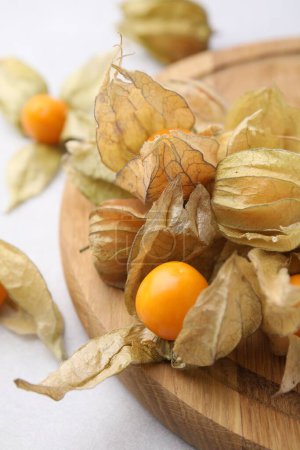 Ripe physalis fruits with calyxes on white table, closeup