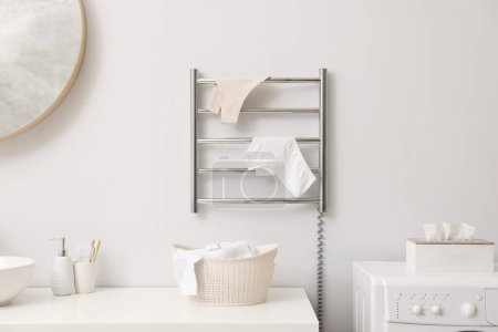 Beheizter Handtuchhalter mit Unterwäsche an weißer Wand im Badezimmer