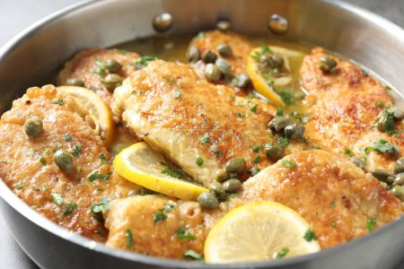 Delicious chicken piccata with herbs in pot, closeup