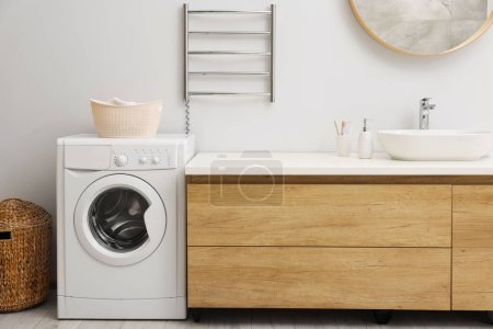Photo for Stylish bathroom interior with heated towel rail and washing machine - Royalty Free Image
