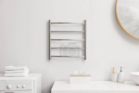 Photo for Heated towel rail on white wall in bathroom - Royalty Free Image