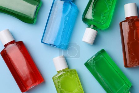 Frische Mundspülungen in Flaschen auf hellblauem Hintergrund, flache Lage