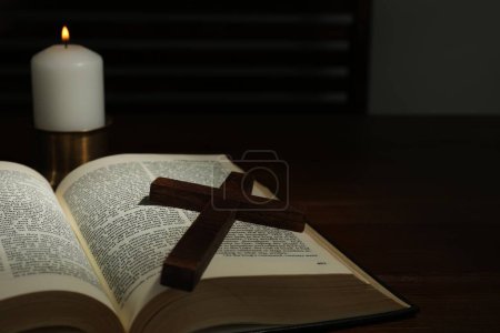 Kreuz, Bibel und Kirchenkerze auf Holztisch