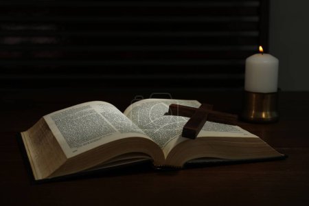 Cruz, Biblia y vela de iglesia sobre mesa de madera