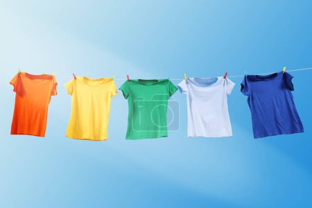Photo for Colorful t-shirts drying on washing line against blue sky - Royalty Free Image