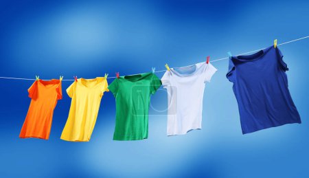 Photo for Colorful t-shirts drying on washing line against blue sky, banner design - Royalty Free Image