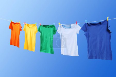 Photo for Colorful t-shirts drying on washing line against blue sky - Royalty Free Image