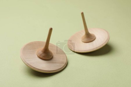 Two wooden spinning tops on green background, closeup