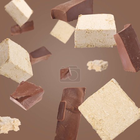 Pieces of tasty halva and chocolate falling on brown background