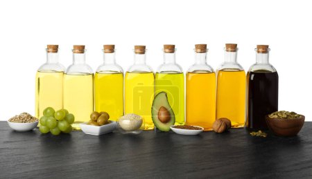 Foto de Grasas vegetales. Frascos de diferentes aceites de cocina e ingredientes sobre mesa de madera sobre fondo blanco - Imagen libre de derechos