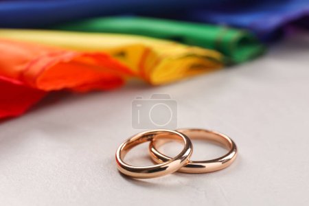 Rainbow LGBT flag and wedding rings on white background, closeup