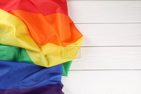 Bandera Rainbow LGBT en mesa de madera blanca, vista superior. Espacio para texto
