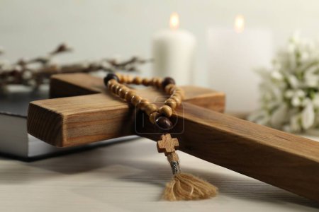 Holzkreuz und Rosenkranzperlen auf weißem Tisch, Nahaufnahme
