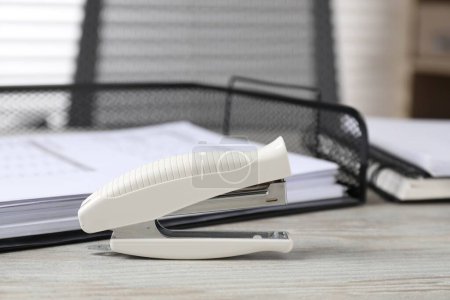 Stapler on wooden table, closeup. Office stationery