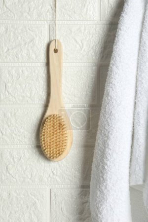 Photo for Bath accessories. Bamboo brush and terry towel on white brick wall - Royalty Free Image
