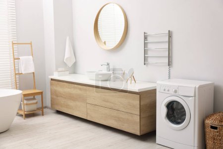 Stylish bathroom interior with heated towel rail and washing machine