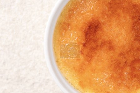 Deliciosa crema brulee en tazón en la mesa de textura ligera, vista superior. Espacio para texto