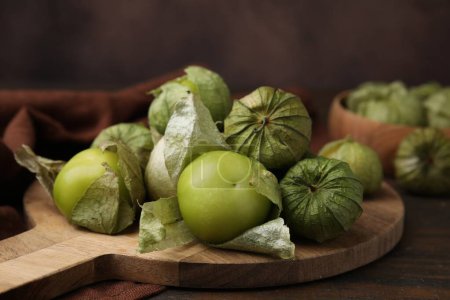 Fresh green tomatillos with husk on wooden table, closeup