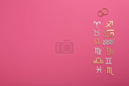 Zodiac compatibility. Signs with wedding rings on pink background, flat lay. Space for text