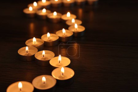 Téléchargez les photos : Brûler des bougies sur une table en bois dans l'obscurité, espace pour le texte - en image libre de droit