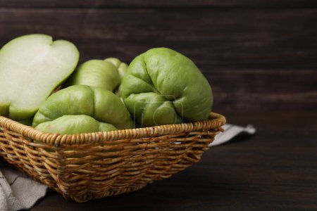 Photo for Cut and whole chayote in wicker basket on wooden table, closeup - Royalty Free Image
