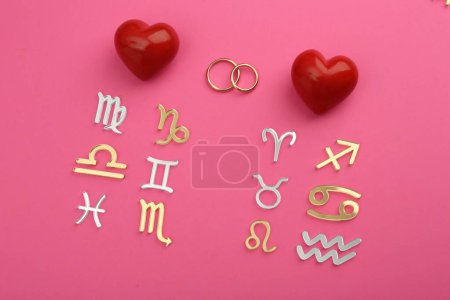 Foto de Compatibilidad con el zodiaco. Signos, anillos de boda y corazones rojos sobre fondo rosa, planas - Imagen libre de derechos