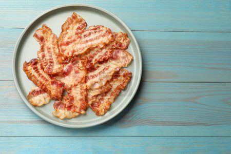 Photo for Delicious fried bacon slices on blue wooden table, top view. Space for text - Royalty Free Image