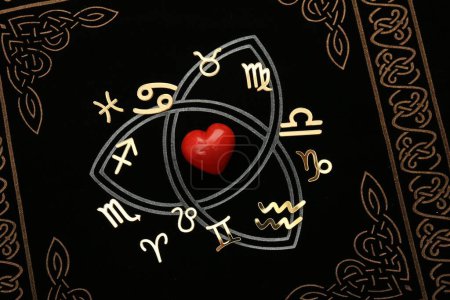 Zodiac signs and red heart on book, flat lay