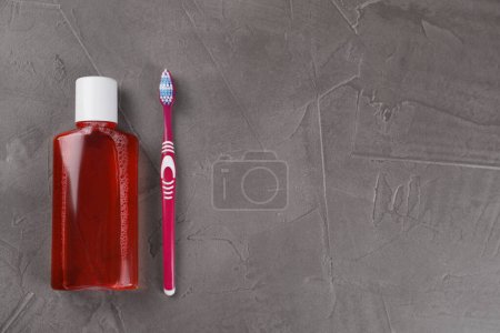 Foto de Enjuague bucal fresco en botella y cepillo de dientes en mesa texturizada gris, vista superior. Espacio para texto - Imagen libre de derechos