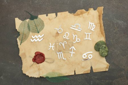 Zodiac signs, stones and old paper on grey textured table, flat lay