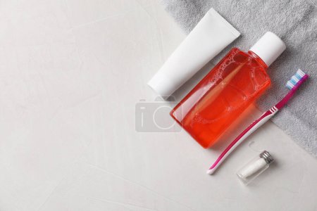 Foto de Enjuague bucal fresco en botella, pasta de dientes, cepillo de dientes y hilo dental sobre fondo de textura clara, puesta plana. Espacio para texto - Imagen libre de derechos