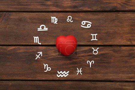 Foto de Signos del zodíaco y corazón rojo sobre fondo de madera, acostado plano - Imagen libre de derechos