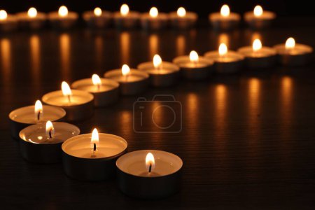 Téléchargez les photos : Bougies allumées sur une table en bois dans l'obscurité, gros plan - en image libre de droit