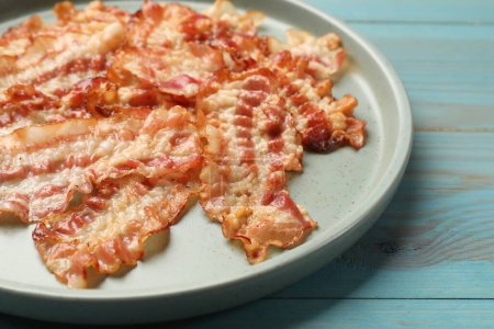 Photo for Delicious fried bacon slices on blue wooden table, closeup - Royalty Free Image