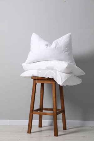 Soft pillows on chair neal light grey wall indoors