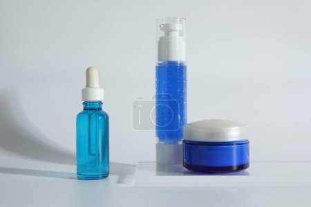 Diferentes recipientes con productos cosméticos sobre fondo claro