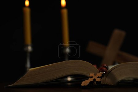 Photo for Wooden cross, rosary beads, Bible and church candles on table, closeup - Royalty Free Image