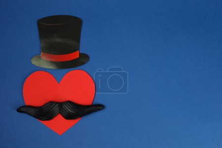 Téléchargez les photos : Fausse moustache, chapeau en papier et coeur sur fond bleu, vue de dessus. Espace pour le texte - en image libre de droit