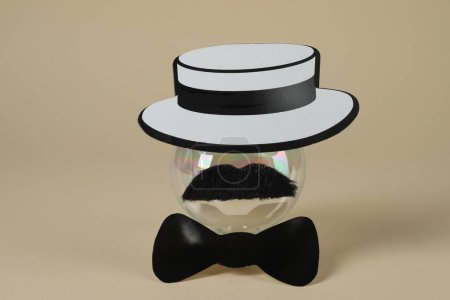 Téléchargez les photos : Visage d'homme en fausse moustache, boule, chapeau et noeud papillon sur fond beige - en image libre de droit