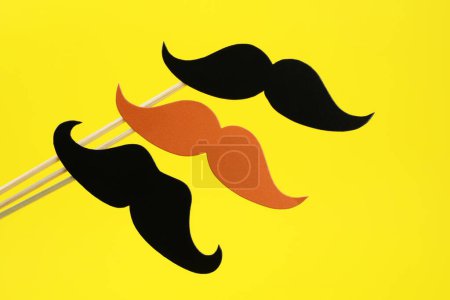 Téléchargez les photos : Fausses moustaches en papier sur bâtons sur fond jaune - en image libre de droit