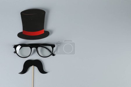 Téléchargez les photos : Fausse moustache avec accessoire de fête, chapeau en papier et lunettes sur fond gris, vue de dessus. Espace pour le texte - en image libre de droit
