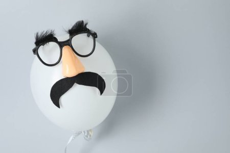 Téléchargez les photos : Visage d'homme en ballon, masque drôle avec fausse moustache, nez et lunettes sur fond gris, vue de dessus. Espace pour le texte - en image libre de droit