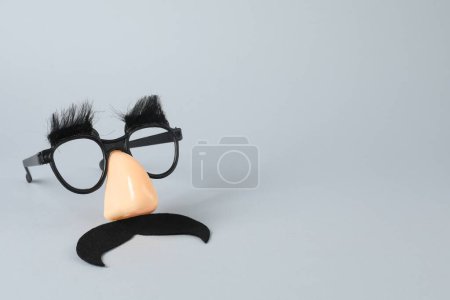 Téléchargez les photos : Masque drôle avec fausse moustache, nez et lunettes sur fond gris, espace pour le texte - en image libre de droit