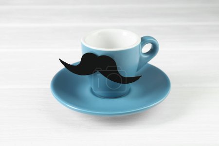 Téléchargez les photos : Coupe avec fausse moustache en papier et soucoupe sur table en bois blanc - en image libre de droit
