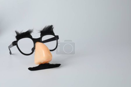 Téléchargez les photos : Masque drôle avec fausse moustache, nez et lunettes sur fond gris clair. Espace pour le texte - en image libre de droit
